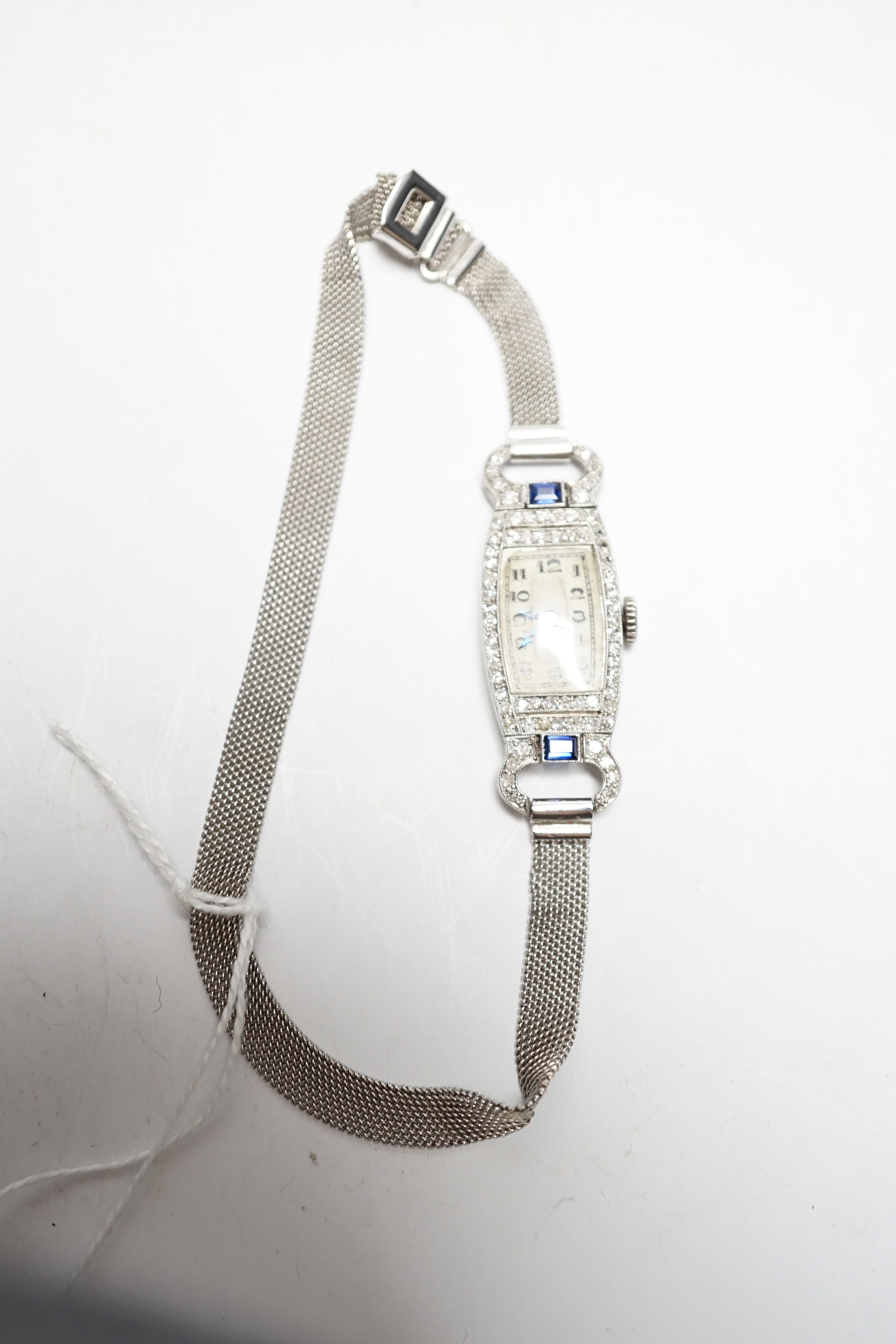 A lady's mid 20th century white metal (Swiss platinum mark), sapphire and diamond cluster set manual wind cocktail watch, with Arabic dial, on and adjustable 9ct mesh link bracelet, gross weight 18 grams.